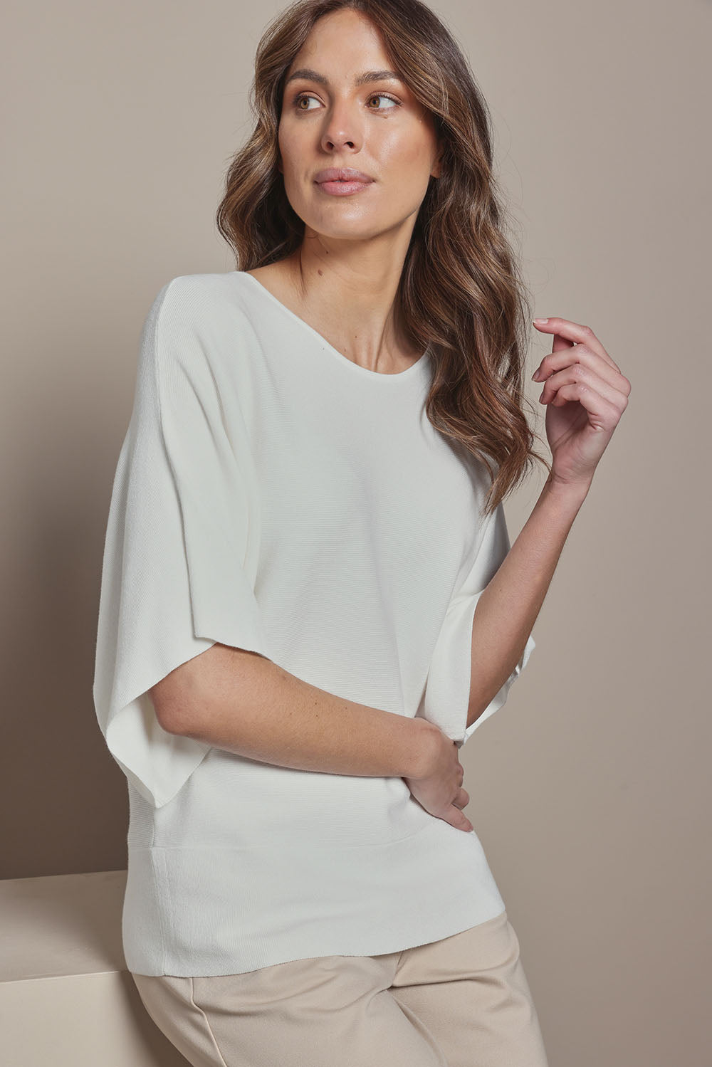 Model Madeline wearing size S of The Transeasonal Kimono Knit in colour Snow (White), from the front, cropped image