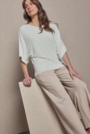 Model Madeline wearing size S of The Transeasonal Kimono Knit in colour Snow (White), from the front, cropped image