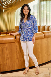 Model Miranda wearing size 10 of The Printed Knot Waist Detail Blouse in colour Fern (Blue), from the front, showing the whole outfit