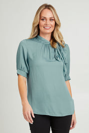 Model Grace wearing size 10 of The Luxe Tie Neck Blouse in colour Duckegg (Blue), from the front, cropped image