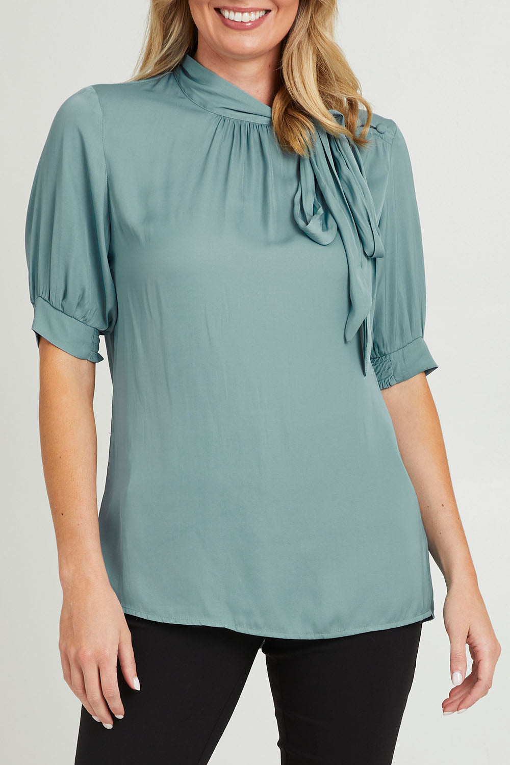 Model Grace wearing size 10 of The Luxe Tie Neck Blouse in colour Duckegg (Blue), from the front, cropped image