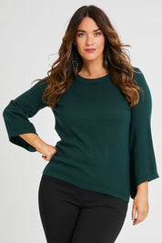 Model Laura wearing size L of The Cotton Cashmere Angled Sleeve Knit in colour Darkpine (Green), from the front, cropped image