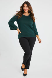 Model Laura wearing size L of The Cotton Cashmere Angled Sleeve Knit in colour Darkpine (Green), from the front, showing the whole outfit