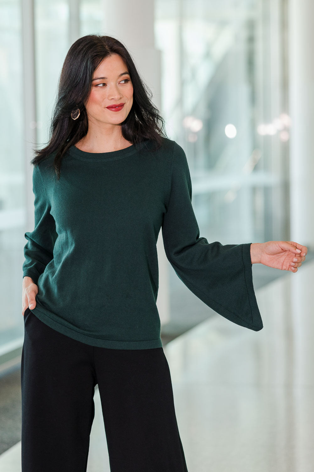 Model Miranda wearing size S of The Cotton Cashmere Angled Sleeve Knit in colour Darkpine (Green), from the front, showing the whole outfit