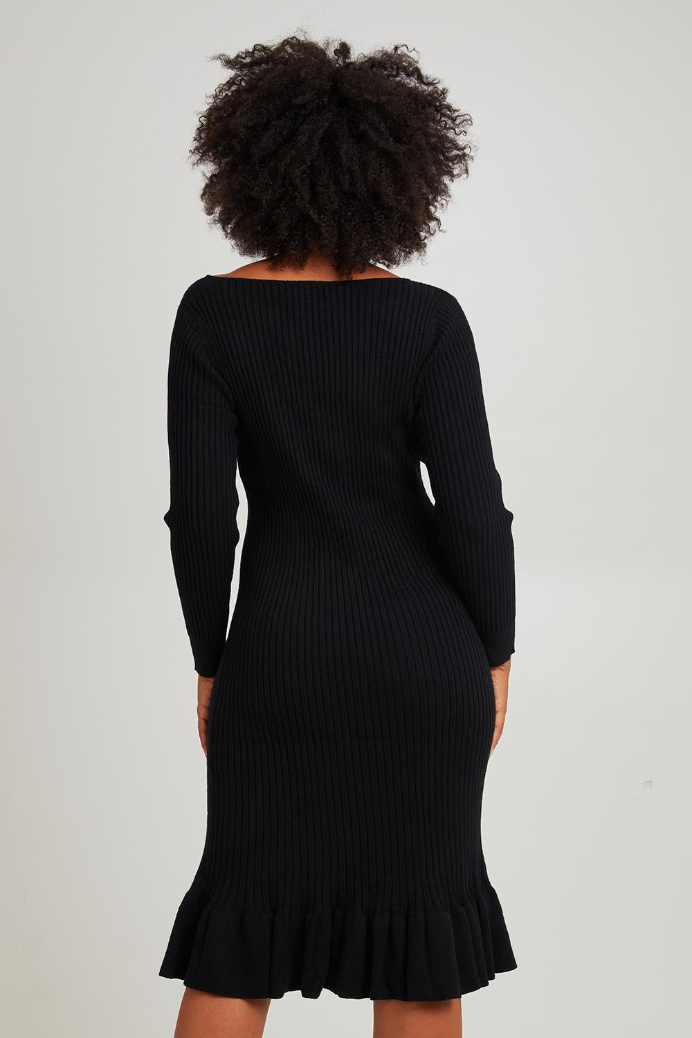 Model Olivia wearing size S of The Ruffle Hem Knitted Rib Dress in colour Black (Black), from the back