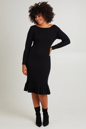 Model Olivia wearing size S of The Ruffle Hem Knitted Rib Dress in colour Black (Black), from the front, showing the whole outfit