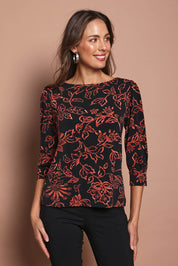 Model Madeline wearing size 10 of The Printed Boat Neck Blouse in colour Emberfleur (Black), from the front, cropped image