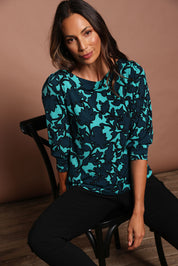 Model Amanda wearing size 10 of The Printed Boat Neck Blouse in colour Tealfleur (Green), from the front, cropped image