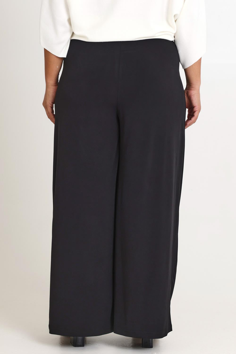 Model Ashleigh wearing size 16 of The Palazzo Jersey Pull On Pant in colour Black (Black), from the back