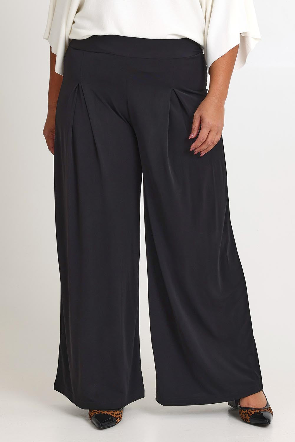 Model Ashleigh wearing size 16 of The Palazzo Jersey Pull On Pant in colour Black (Black), from the front, cropped image
