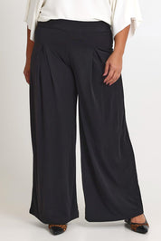 Model Ashleigh wearing size 16 of The Palazzo Jersey Pull On Pant in colour Black (Black), from the front, cropped image