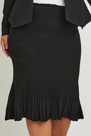 Model Ashleigh wearing size XL of The Textured Knit Frill Skirt in colour Black (Black), from the front, cropped image
