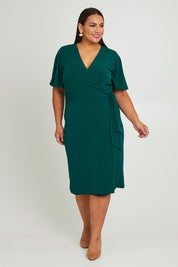 Model Ashleigh wearing size 16 of The Mock Wrap Dress in colour Pine (Green), from the front, showing the whole outfit
