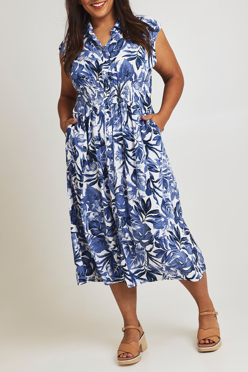 Model Ashleigh wearing size 16 of The Shirred Waist Button Through Dress in colour Tropics (Blue), from the front, cropped image
