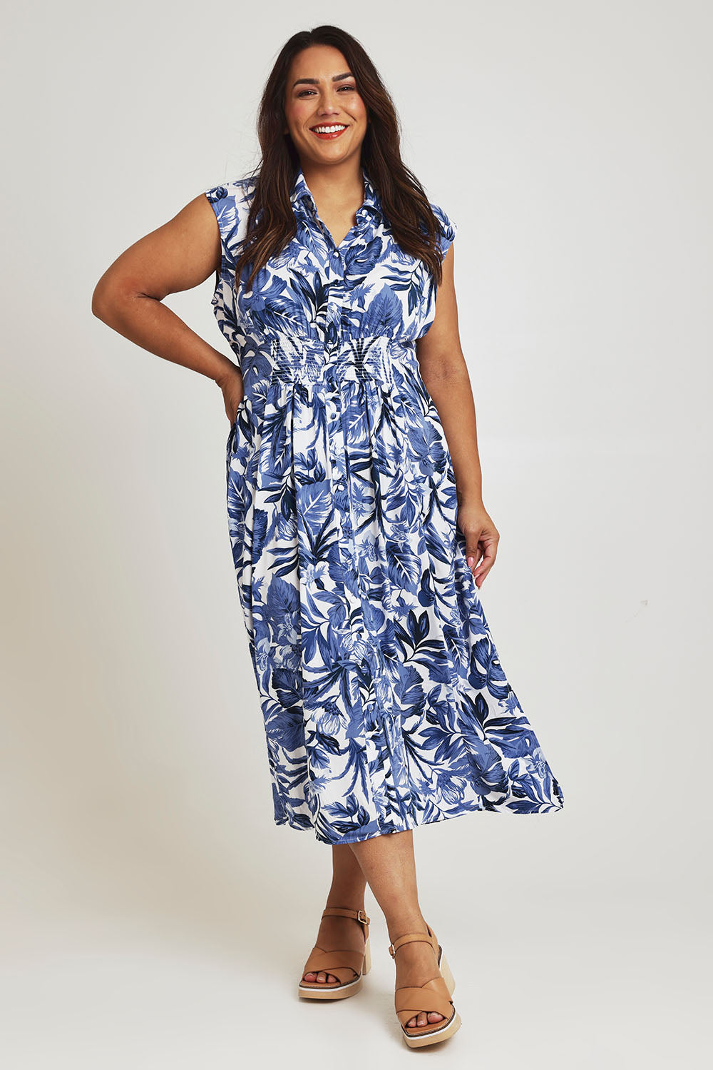 Model Ashleigh wearing size 16 of The Shirred Waist Button Through Dress in colour Tropics (Blue), from the front, showing the whole outfit