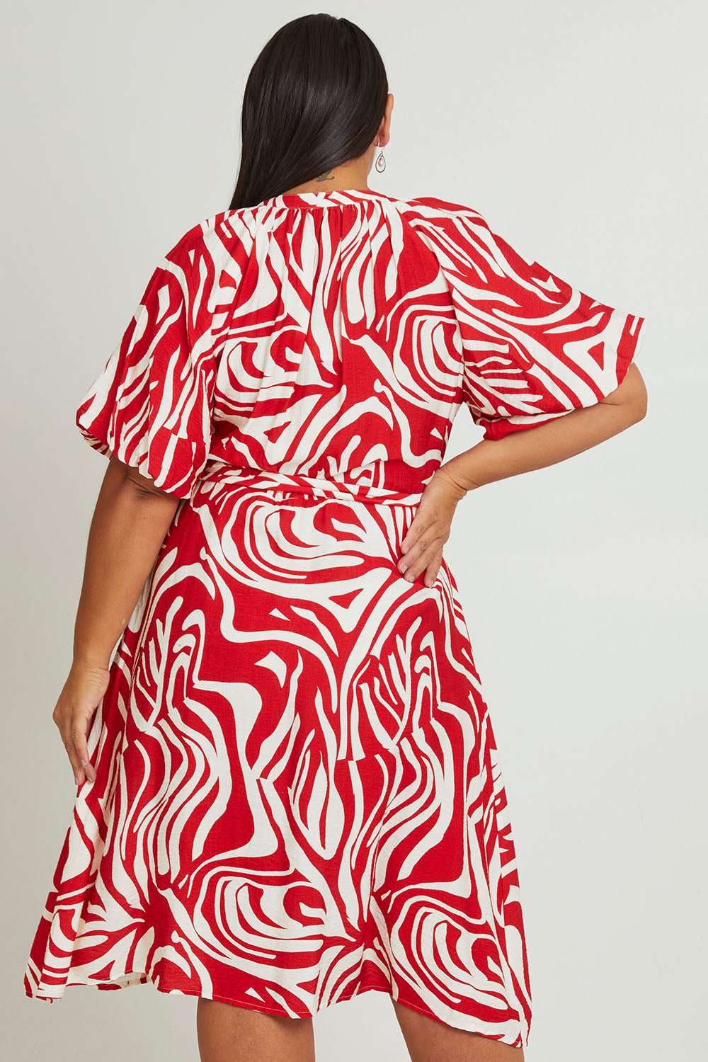 Model Ashleigh wearing size 16 of The Bubble Sleeve Button Through Dress in colour Abstract (Red), from the back