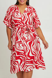 Model Ashleigh wearing size 16 of The Bubble Sleeve Button Through Dress in colour Abstract (Red), from the front, cropped image