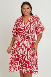 Model Ashleigh wearing size 16 of The Bubble Sleeve Button Through Dress in colour Abstract (Red), from the front, cropped image