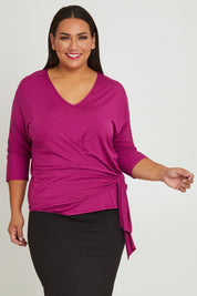 Model Ashleigh wearing size 16 of The Bamboo Tie Waist Top in colour Berry (Pink), from the front, cropped image
