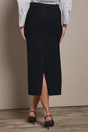 Model Madeline wearing size S of The Crepe Knit Multiway Pull On Skirt in colour Black (Black), from the back