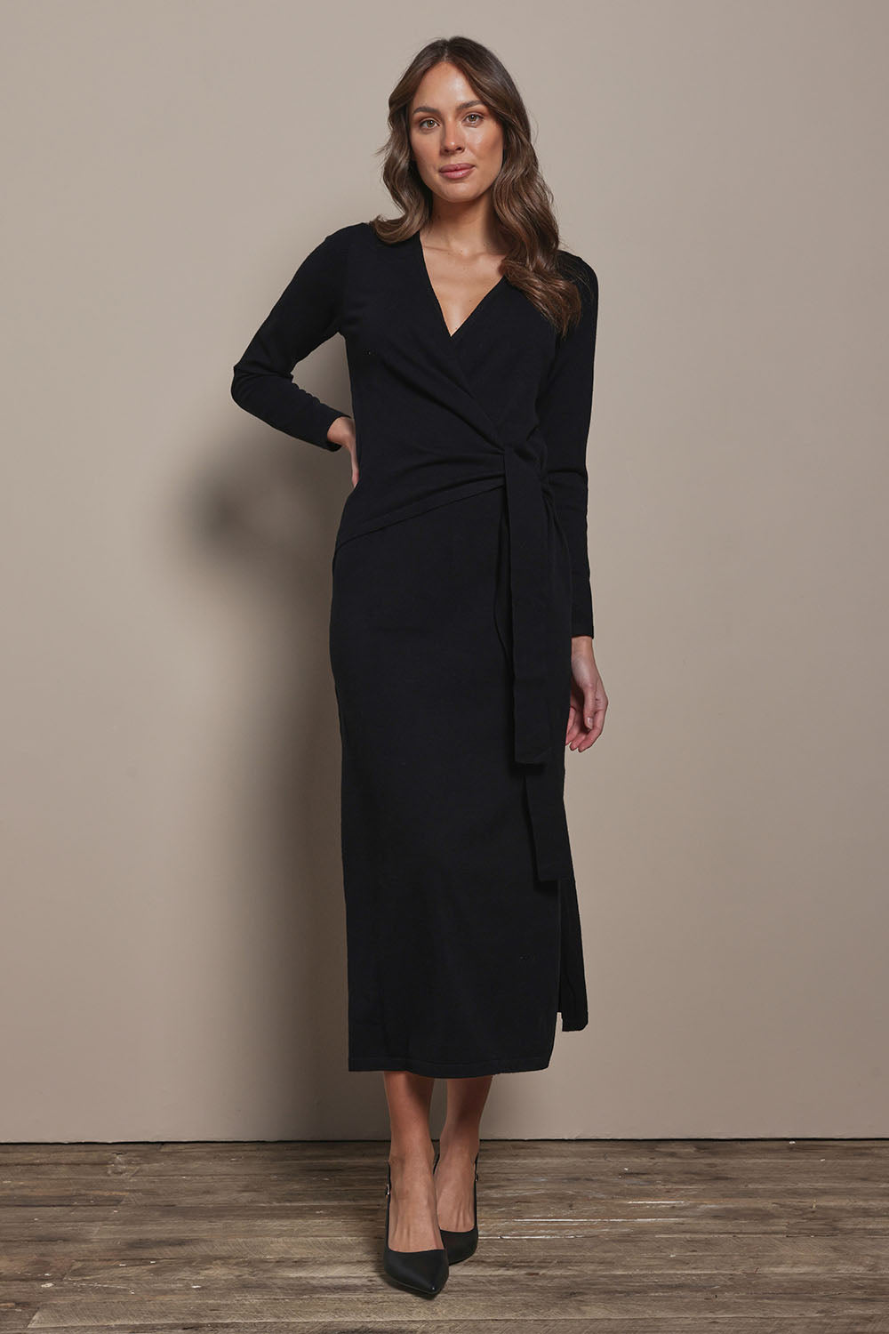 Model Madeline wearing size S of The Tie Waist Faux Wrap Knit Dress in colour Black (Black), from the front, showing the whole outfit
