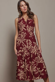 Model Madeline wearing size 10 of The Printed Sleeveless Wrap Dress in colour Winefleur (Red), from the front, cropped image