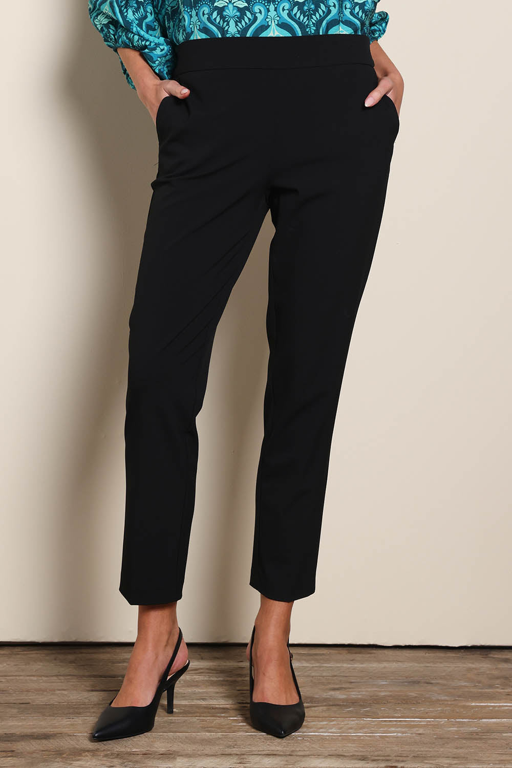 Model Madelinec wearing size 10 of the The Tapered Pull On Stretch Pant – Black in colour Black, in a cropped view