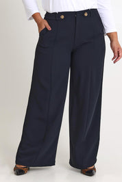 Model Ashleigh wearing size 16 of The Tab Detail Tailored Pant in colour Black (Black), from the front, cropped image