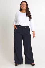 Model Ashleigh wearing size 16 of The Tab Detail Tailored Pant in colour Black (Black), from the front, showing the whole outfit