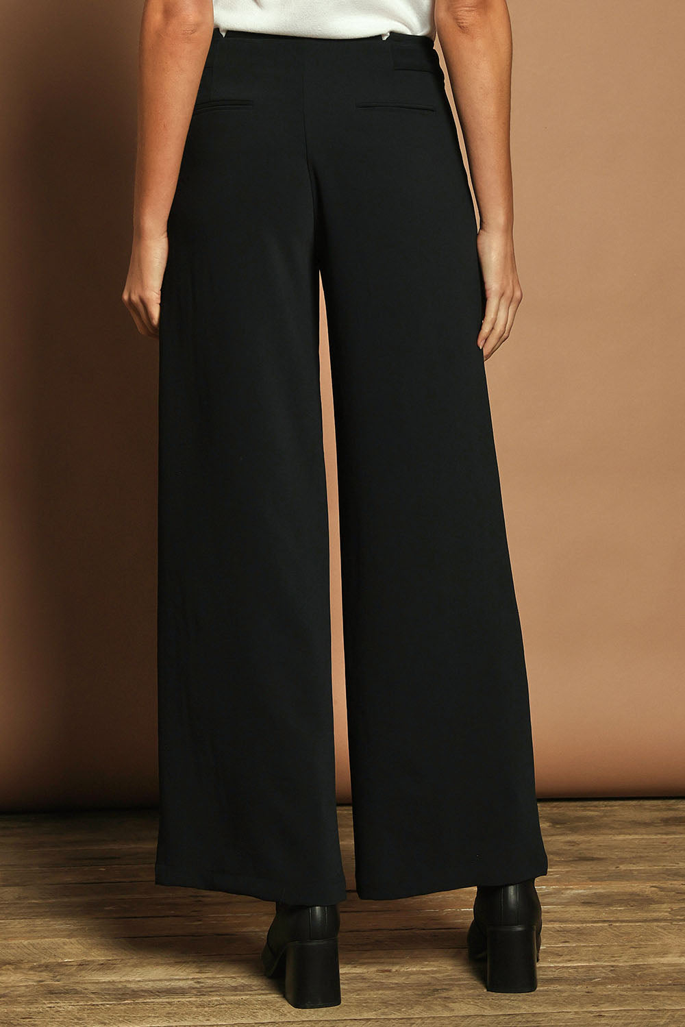 Model Madeline wearing size 10 of The Tab Detail Tailored Pant in colour Black (Black), from the back