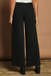 Model Madeline wearing size 10 of The Tab Detail Tailored Pant in colour Black (Black), from the back