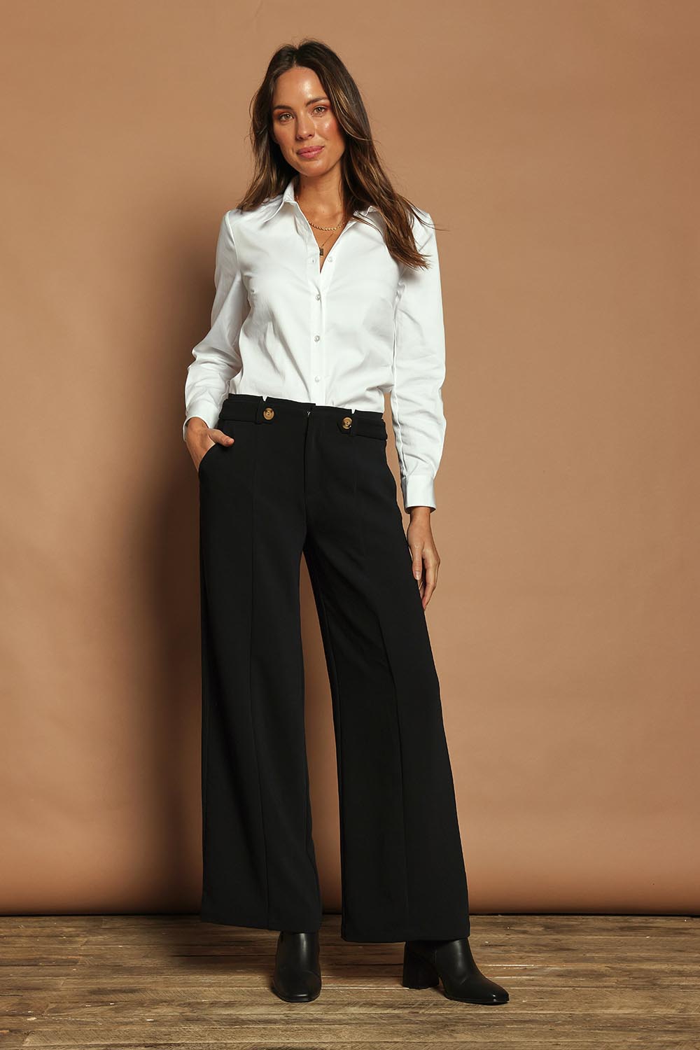 Model Madeline wearing size 10 of The Tab Detail Tailored Pant in colour Black (Black), from the front, showing the whole outfit