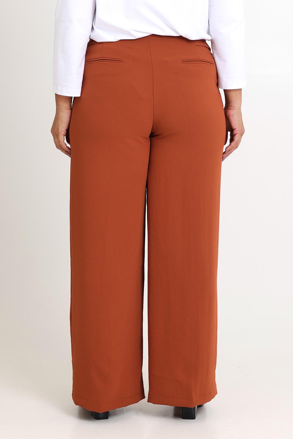 Model Ashleigh wearing size 16 of The Tab Detail Tailored Pant in colour Rust, from the back