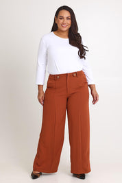 Model Ashleigh wearing size 16 of The Tab Detail Tailored Pant in colour Rust, from the front, showing the whole outfit