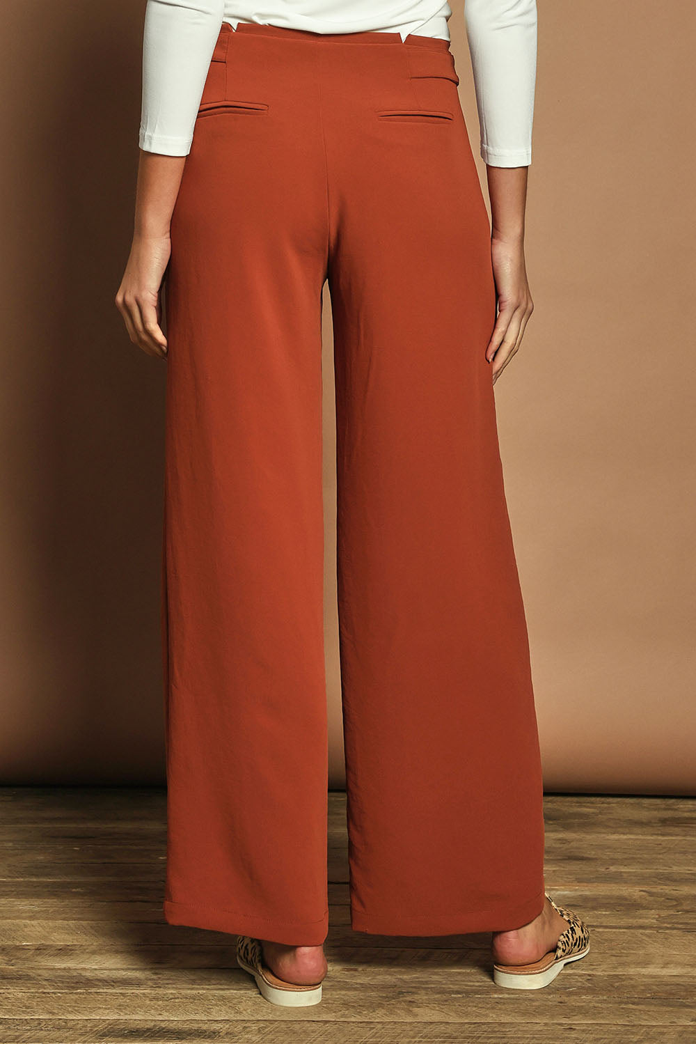 Model Madeline wearing size 10 of The Tab Detail Tailored Pant in colour Rust, from the back