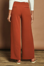 Model Madeline wearing size 10 of The Tab Detail Tailored Pant in colour Rust, from the back