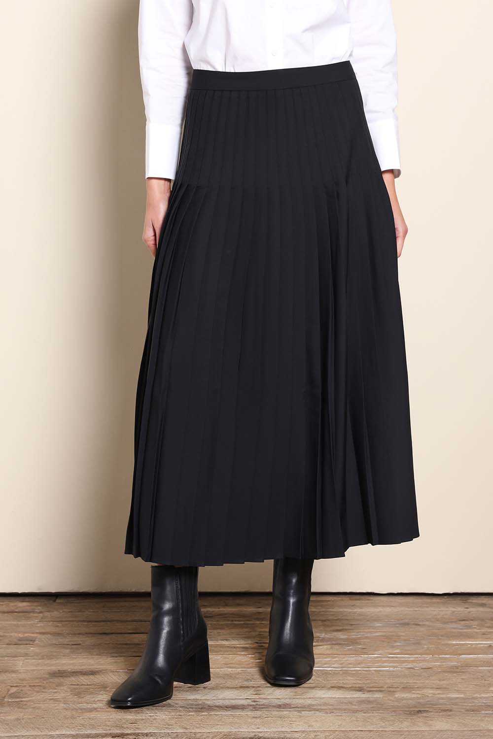 Model Maddiec wearing size 10 of the The Luxe Pleated Skirt – Black in colour Black, in a cropped view