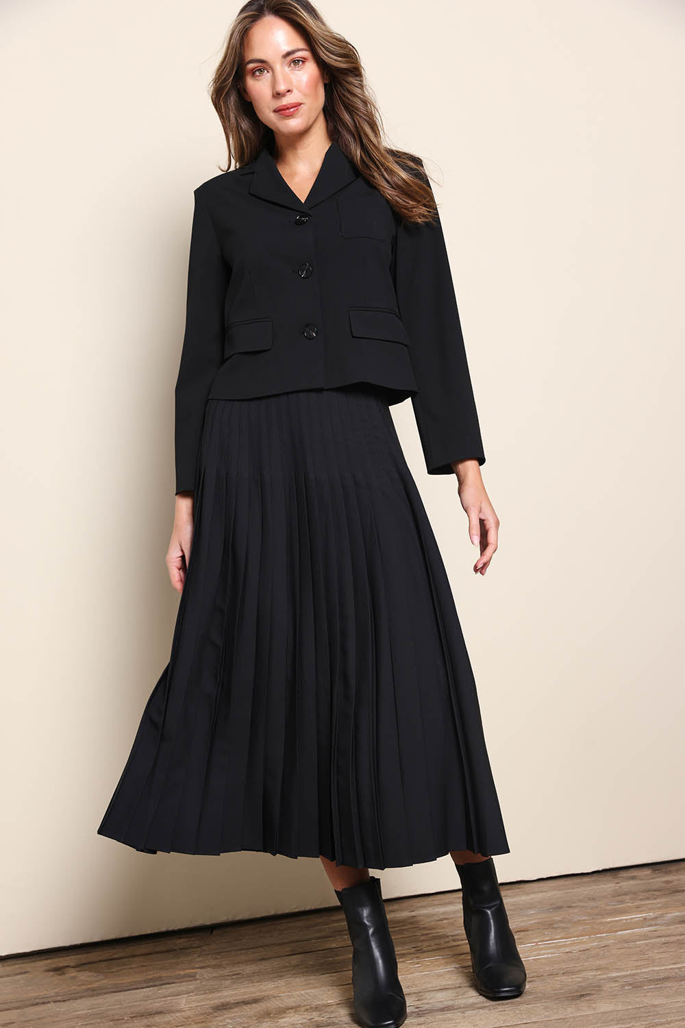 Model Madelinec wearing size 10 of the The Luxe Pleated Skirt – Black in colour Black, from the front
