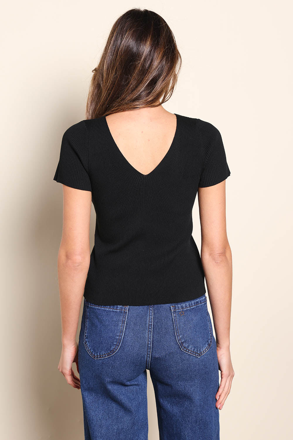 Model Madelinec wearing size 10 of the The Reversible Rib Knit Top – Black in colour Black, from the back