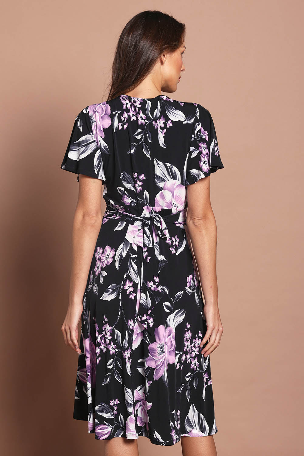 Model Madeline wearing size 10 of The Printed Jersey Faux Wrap Dress in colour Pinkfloral (Black), from the back