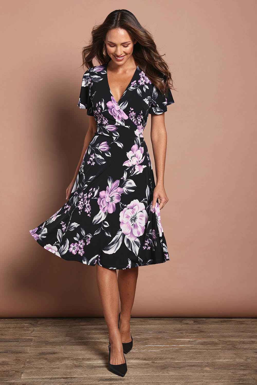 Model Madeline wearing size 10 of The Printed Jersey Faux Wrap Dress in colour Pinkfloral (Black), from the front, showing the whole outfit