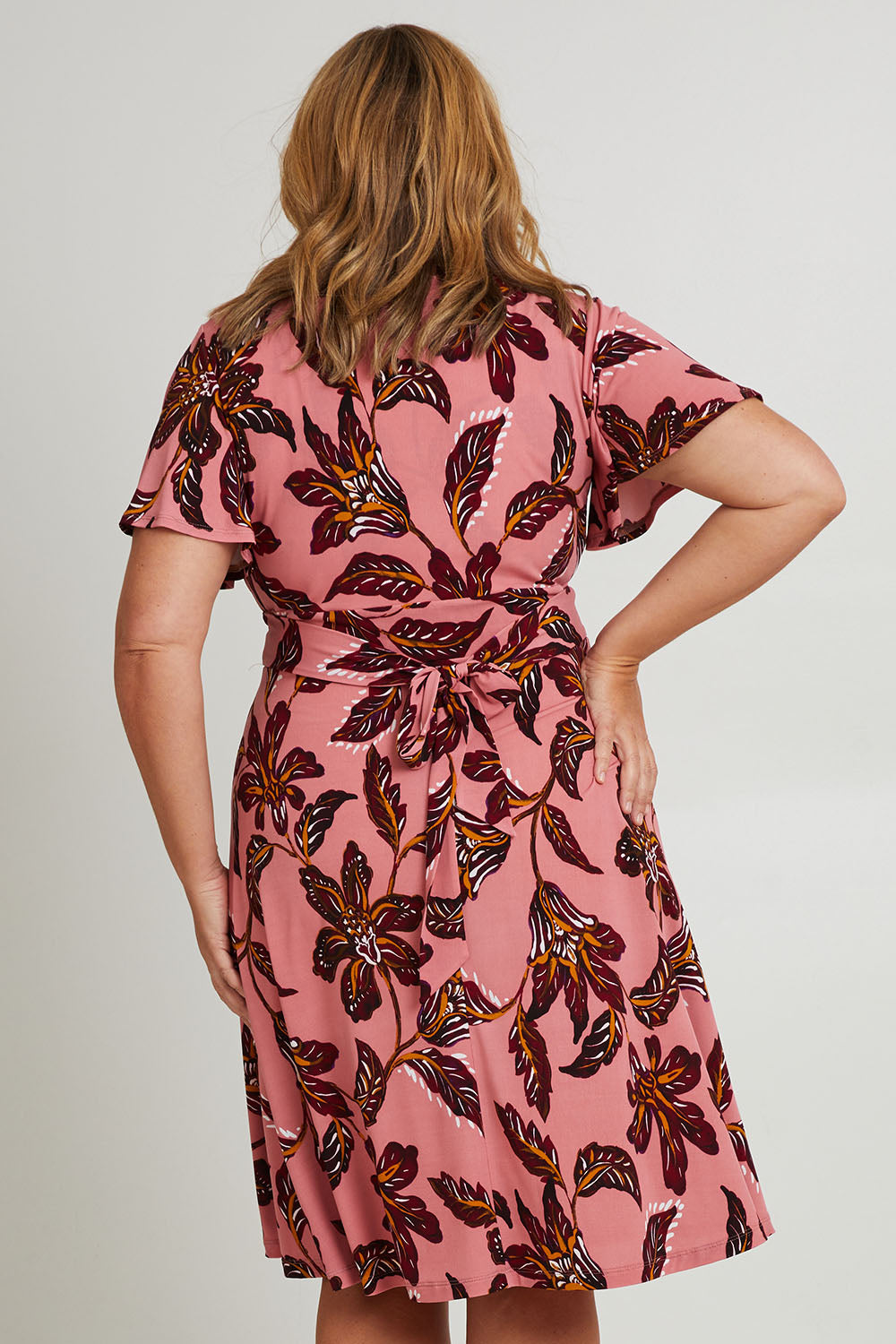 Model Fiona wearing size 16 of The Printed Jersey Faux Wrap Dress in colour Pinkfleur (Pink), from the back