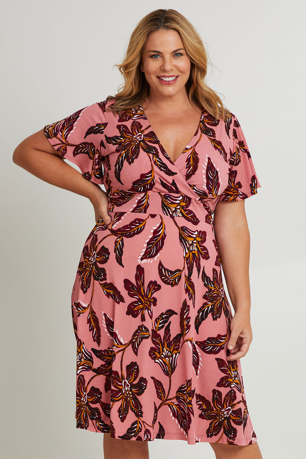 Model Fiona wearing size 16 of The Printed Jersey Faux Wrap Dress in colour Pinkfleur (Pink), from the front, cropped image