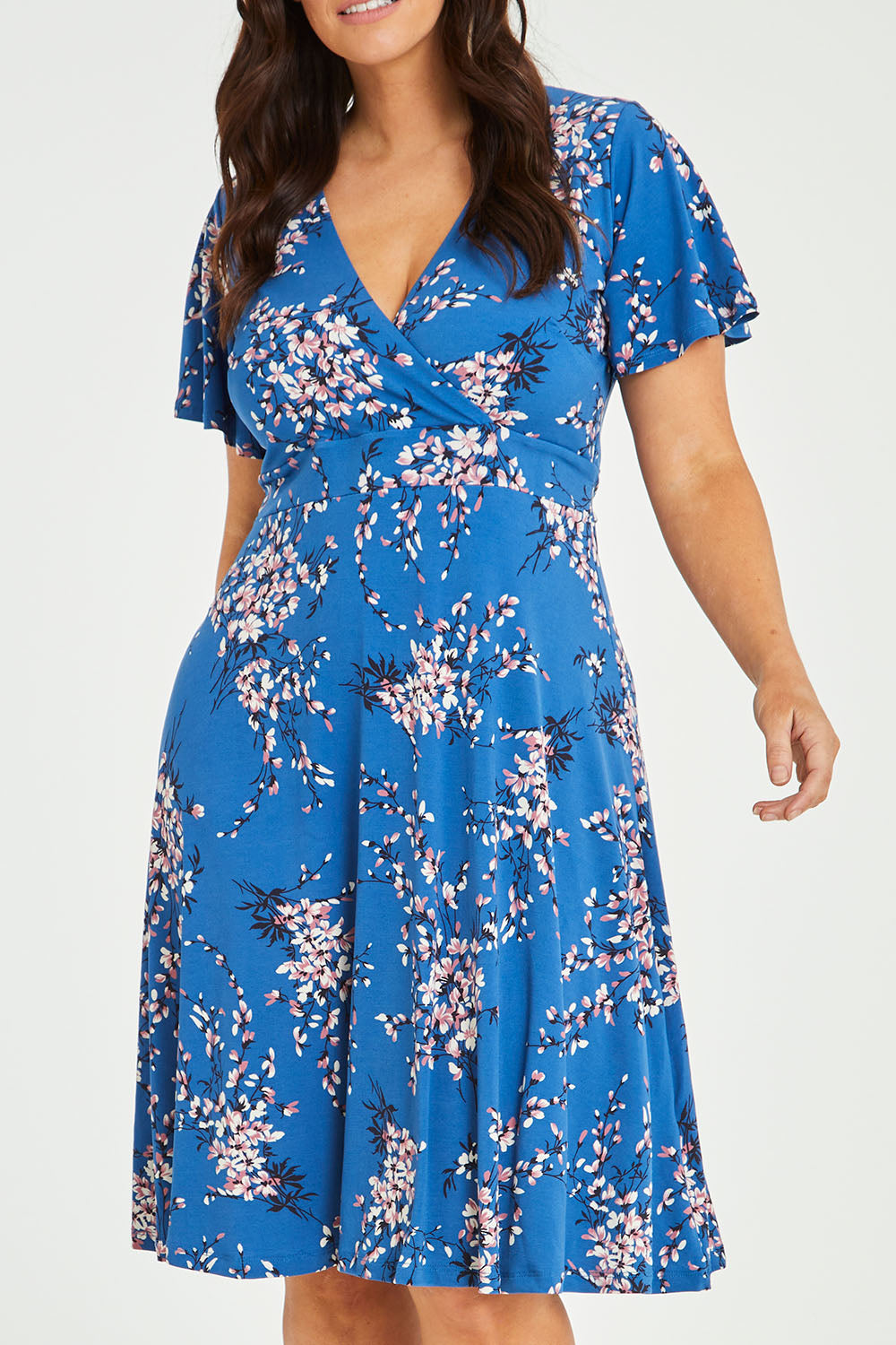 Model Laura wearing size 14 of The Printed Jersey Faux Wrap Dress in colour Blossom (Blue), from the front, cropped image