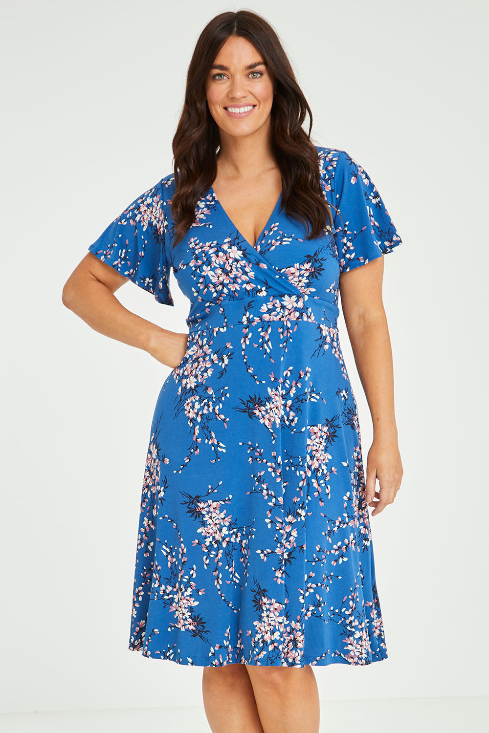 Model Laura wearing size 14 of The Printed Jersey Faux Wrap Dress in colour Blossom (Blue), from the front, cropped image