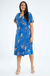 Model Sasha-Lee wearing size 16 of The Printed Jersey Faux Wrap Dress in colour Blossom (Blue), from the front, showing the whole outfit