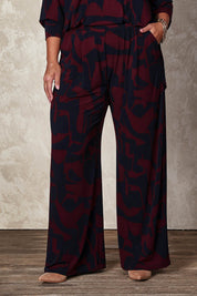 Model Ashleigh wearing size 16 of the Belle Printed Easywear Wide Leg Pant in colour Winenavy (Blue), from the front, cropped image