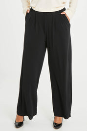 Model Noli wearing size 14 of the Belle Wide Leg Pant in colour Black (Black), from the front, cropped image