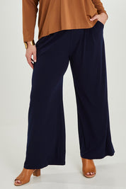 Model Maddy wearing size 16 of the Belle Wide Leg Pant in colour Navy (Blue), from the front, cropped image