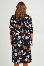Model Monique wearing size 14 of the Belle Heather Floral Wrap Dress in colour Florals (Blue), from the back
